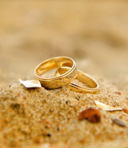 Two wedding rings sitting on top of a beach.