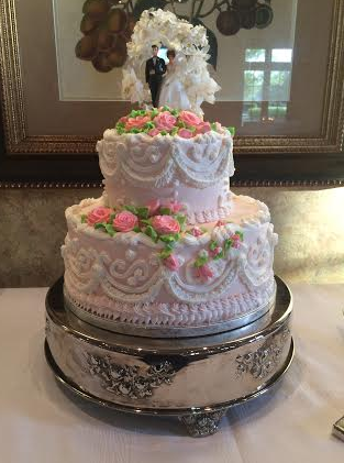 A two tiered cake with pink flowers on top.